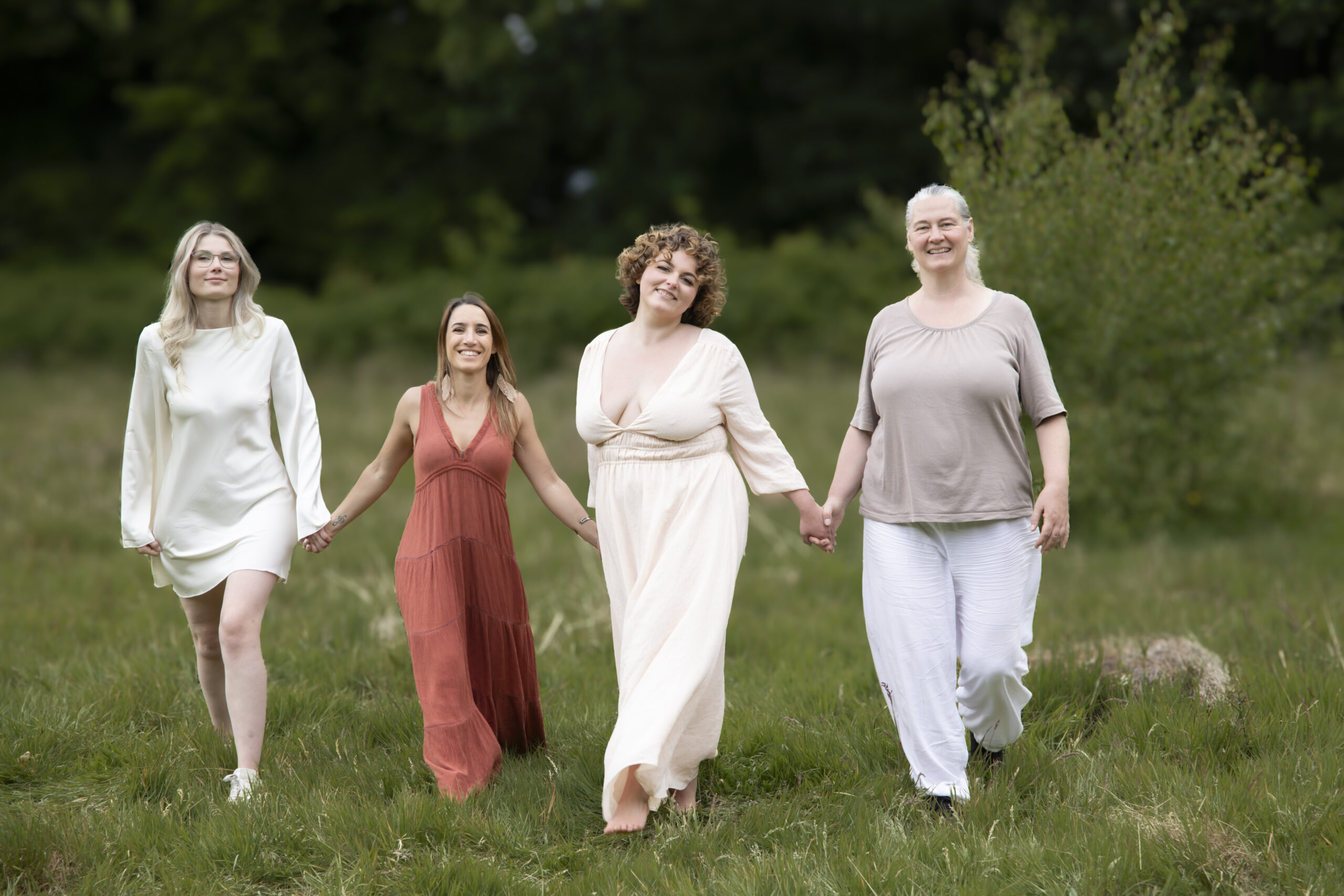 A group of retreat leaders and mentors walking together through a summer meadow, holding hands, photographed by Julia Bader
